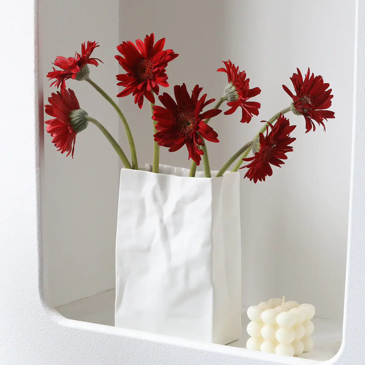 Stylish white ceramic flower vase holding vibrant red flowers for modern home decor