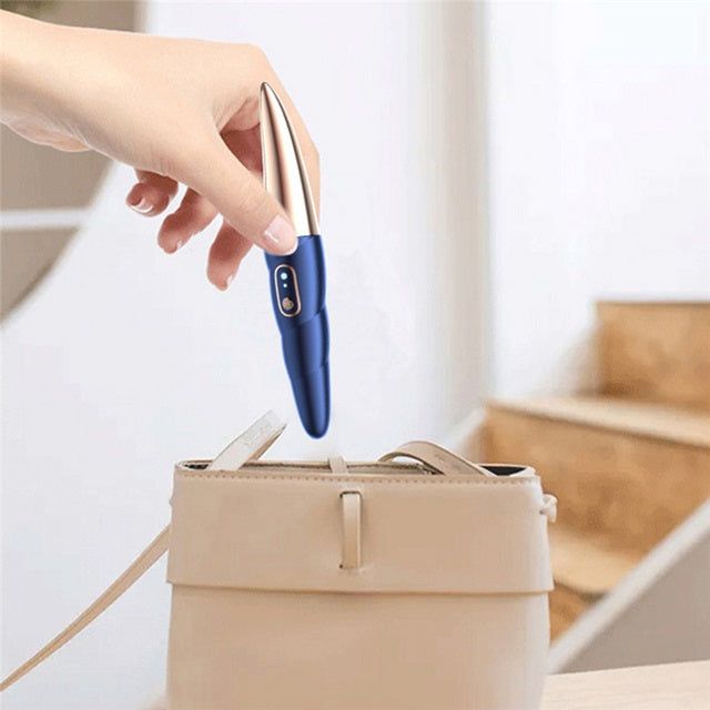 Gizmo Gadgets Electric eyelash curler in a stylish blue design held above a handbag for easy storage