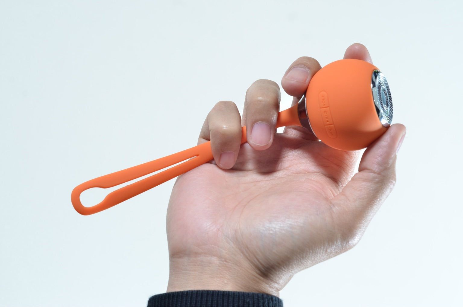 Orange waterproof Bluetooth speaker held in hand with a convenient strap for easy carrying