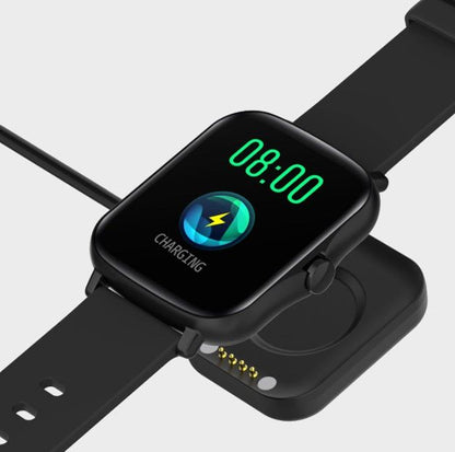 Black smart watch with encoder displaying charging status and digital time on a charging dock